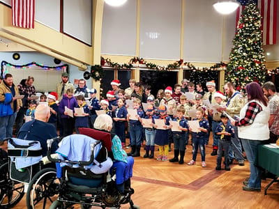 Residents enjoying a holiday performance with children singing