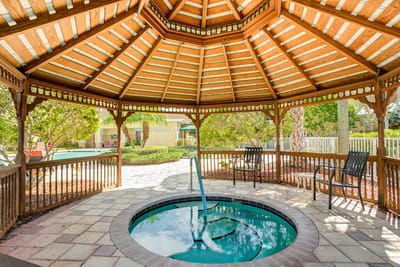 A gazebo with a spa in a landscaped outdoor area
