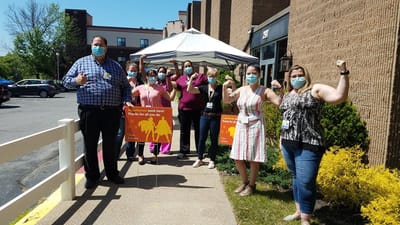 Staff members celebrating outside with signs