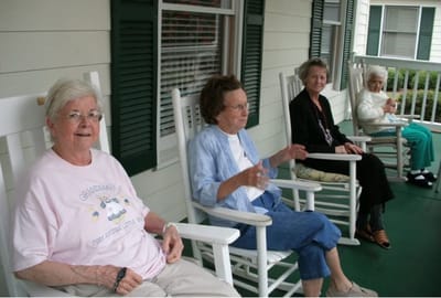 Four senior women sitting in rocking chairs on a porch