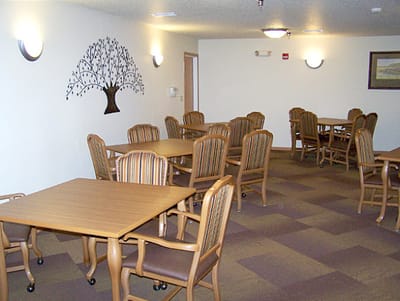Common area with tables and chairs, tree mural on wall