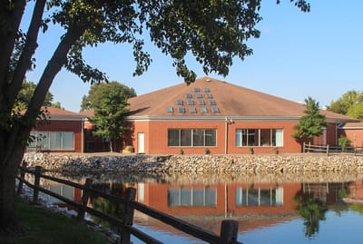Exterior view of a senior living facility by a pond
