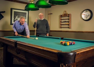 Two residents playing billiards in the activity room