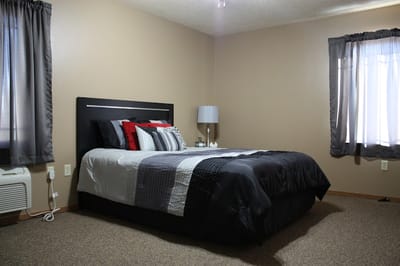 Cozy resident room with a bed, lamp, and windows
