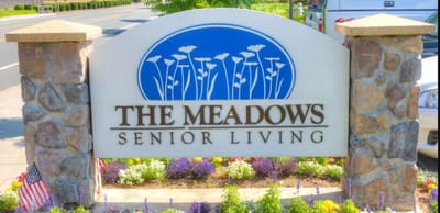 Sign for The Meadows Senior Living with flowers and landscaping