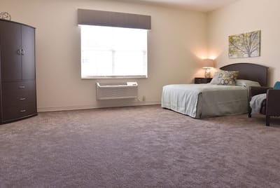 A well-furnished resident room with a bed and chair
