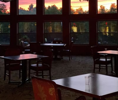 Dining area with tables and a colorful sunset visible
