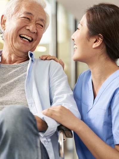 Senior resident laughing with a caregiver.