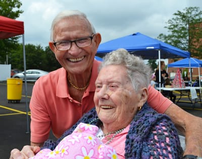Smiling staff member with resident outdoors.