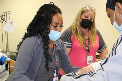 Staff engaging with a training mannequin.