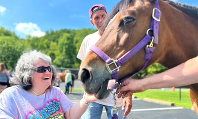Resident interacting with a horse outdoors.