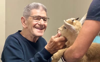 Senior resident interacting with a baby goat.