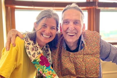 A staff member and resident smiling together indoors.
