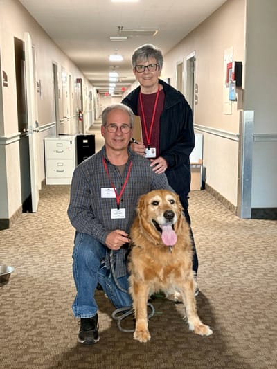 Residents and staff with a dog in the hallway