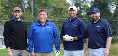 Group of men playing golf outdoors.