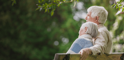 Two elderly individuals sitting together on a bench