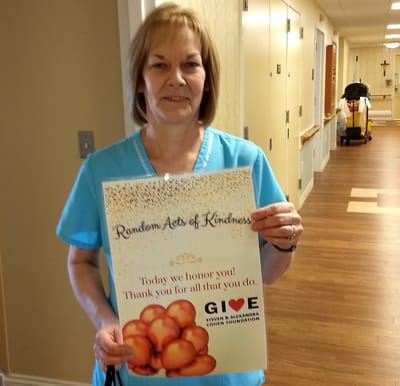 Staff member holding a kindness poster