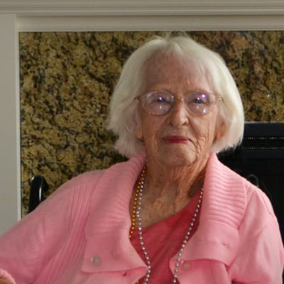 Elderly woman sitting in a cozy interior setting.