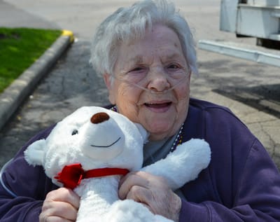Elderly woman smiling with a teddy bear.