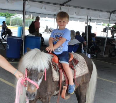 Child riding a pony at a community event.