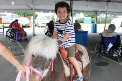 Child riding a pony with seniors in wheelchairs nearby