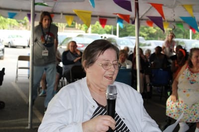 Resident participating in an outdoor event with microphone.