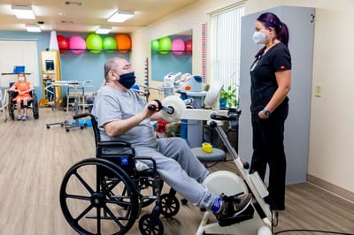 Resident exercising with staff assistance in an activity room