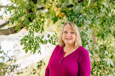 A resident smiling outdoors among greenery