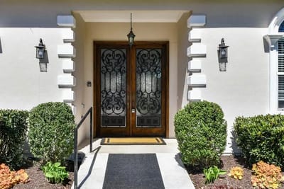 Entrance door with decorative wrought iron and landscaping