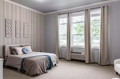 Bright interior of a private resident room with a bed and window