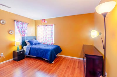 Brightly lit private room with a blue bedspread