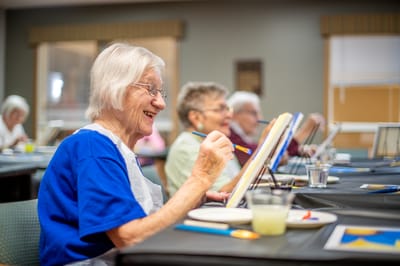 Residents painting in an activity room during a class