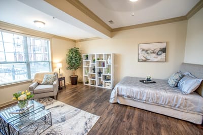 Brightly furnished resident room with a bed and seating area