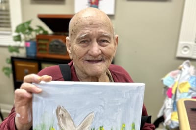 Elderly resident proudly holding a painting