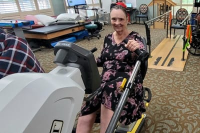 A resident using a therapy bike in an activity room