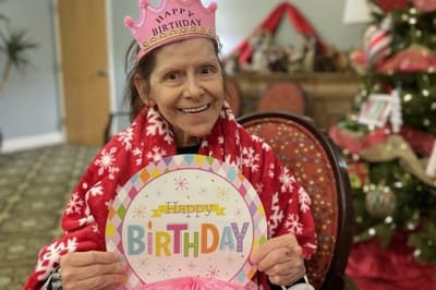 Resident celebrating a birthday with a festive hat and sign