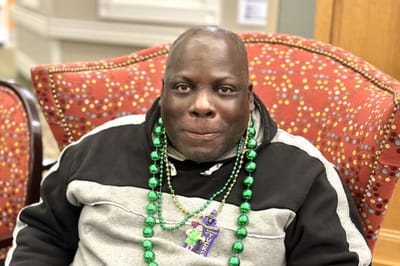 Resident smiling with festive beads in a common area
