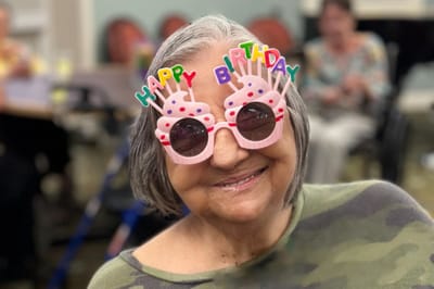 Resident celebrating with festive birthday glasses