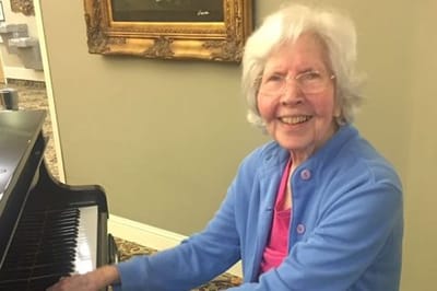 Resident playing piano and smiling