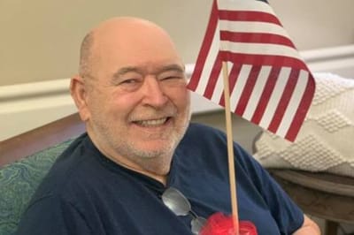 Resident smiling and holding a small American flag