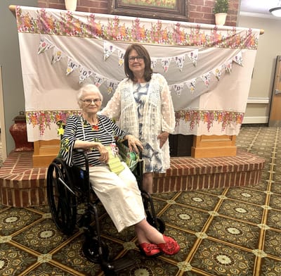 Resident in a wheelchair with a staff member in front of a decoration banner