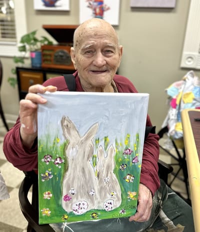 Elderly resident holding a painting of rabbits