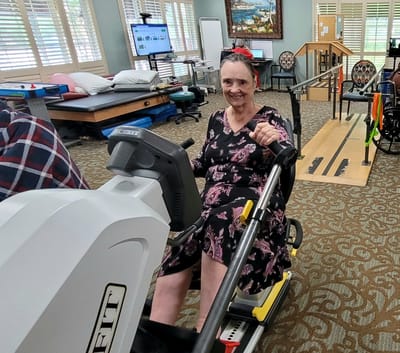 Resident using a recumbent exercise bike in a therapy room