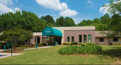 Exterior view of the Delmar Gardens facility with greenery