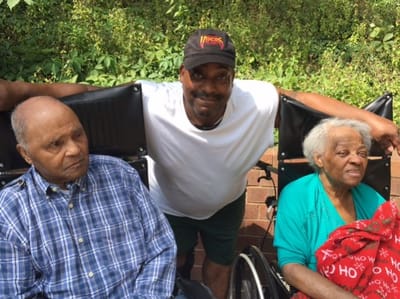 Two residents with a staff member outdoors