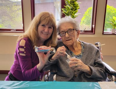 Resident enjoying ice cream with staff member
