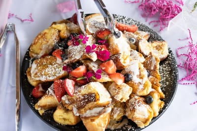 A plate of delicious French toast with fruits and powdered sugar