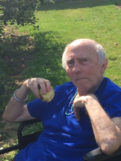 An elderly resident sitting outdoors holding an apple