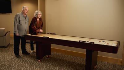 Residents playing a shuffleboard game in an activity room