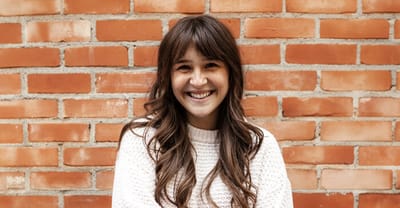 Woman smiling in front of a brick wall